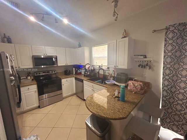 kitchen with a sink, a peninsula, lofted ceiling, rail lighting, and appliances with stainless steel finishes
