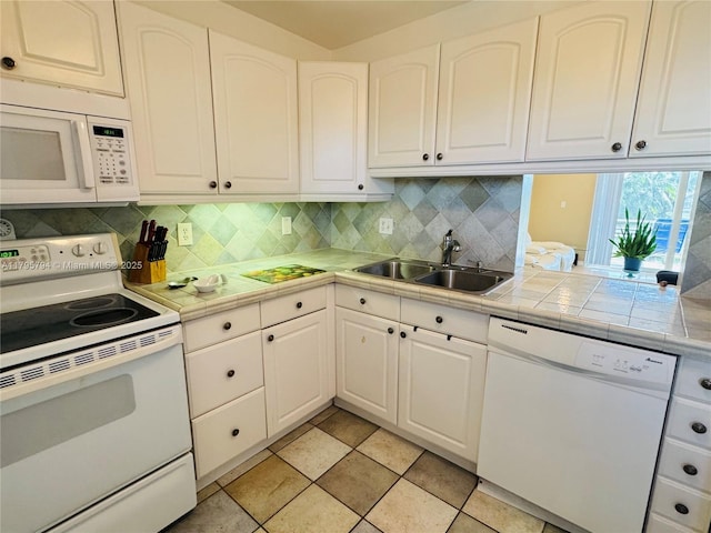 kitchen featuring white appliances, white cabinetry, decorative backsplash, and a sink