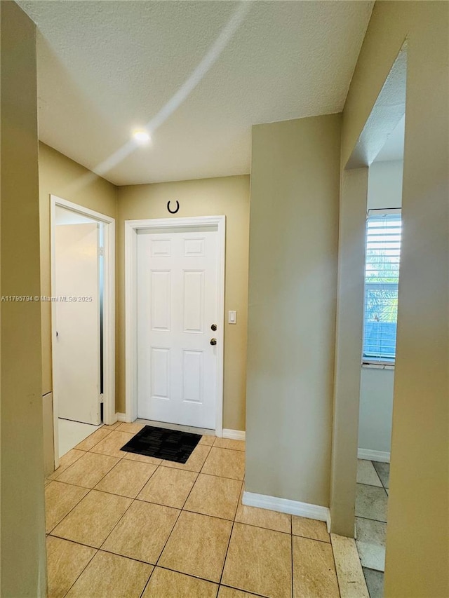 entrance foyer with light tile patterned floors, baseboards, and a textured ceiling