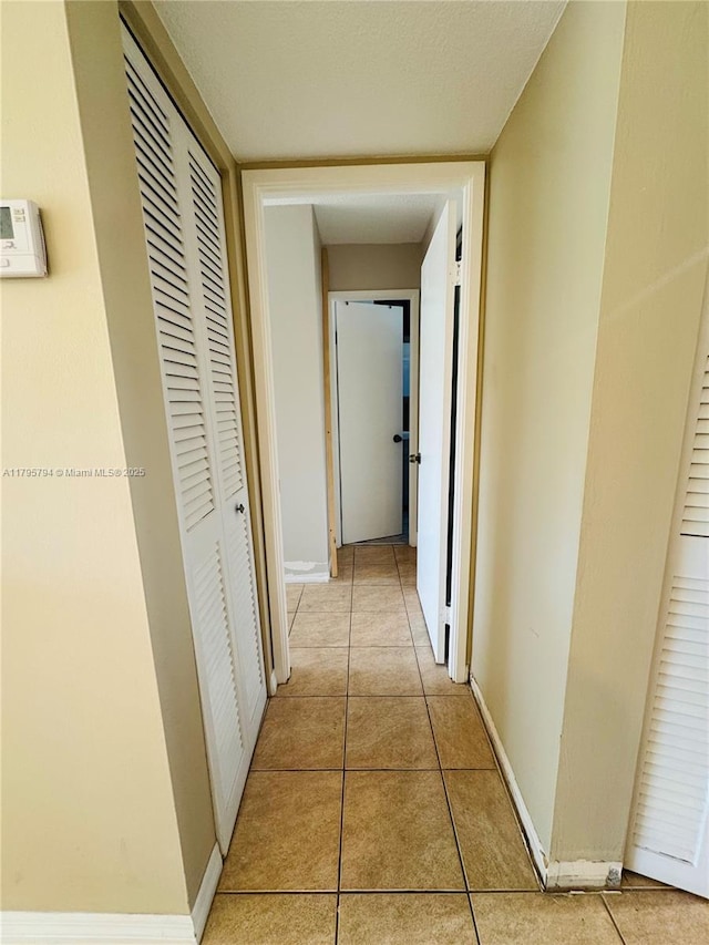 hallway featuring baseboards and light tile patterned flooring