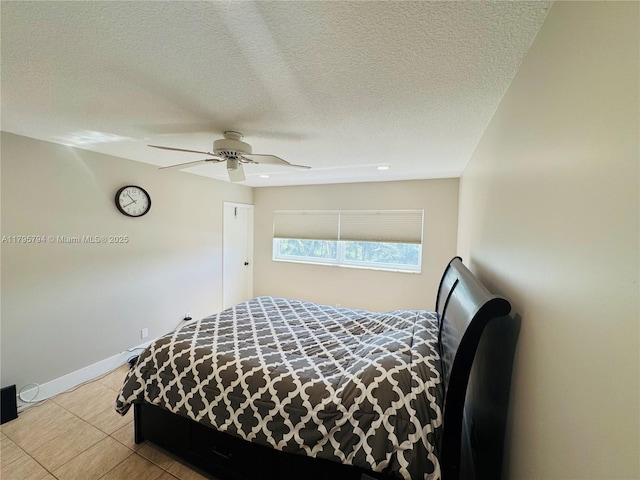 bedroom with tile patterned flooring, a ceiling fan, baseboards, and a textured ceiling
