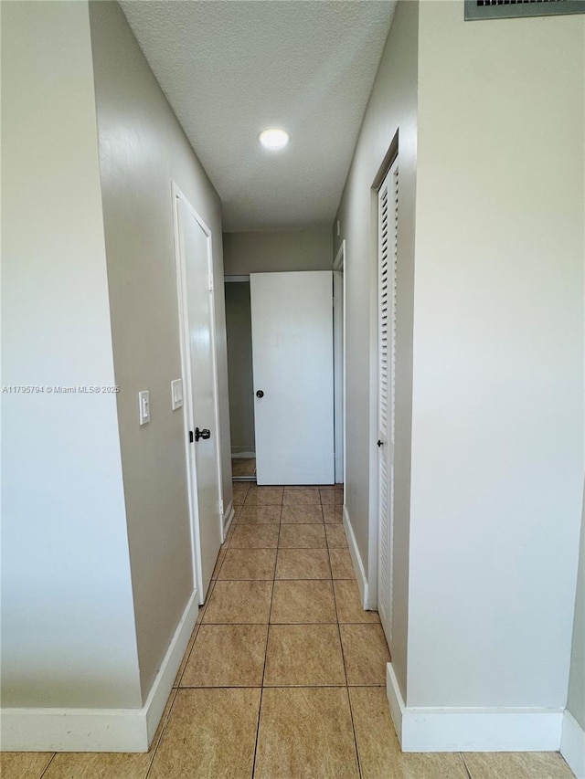 hall with baseboards and light tile patterned floors
