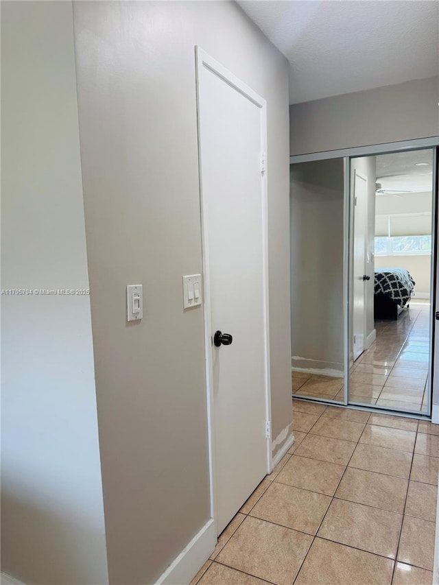 hall with light tile patterned floors and baseboards