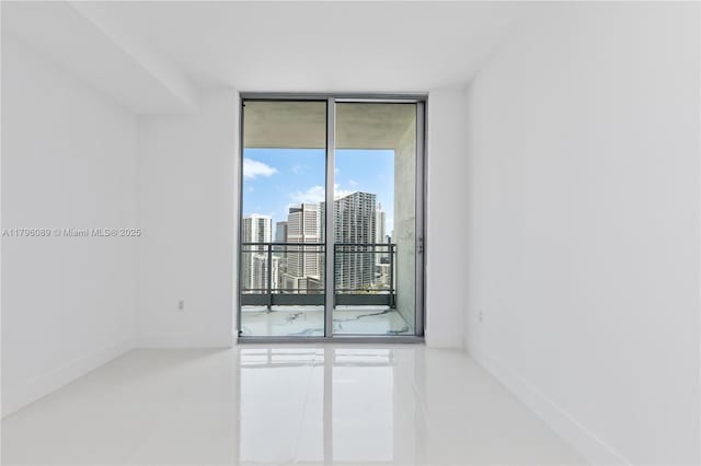 spare room with a wall of windows, tile patterned floors, and a city view