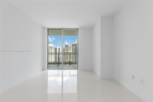 tiled spare room with a wall of windows and baseboards