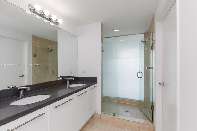 bathroom featuring double vanity, tile patterned floors, a sink, and a stall shower