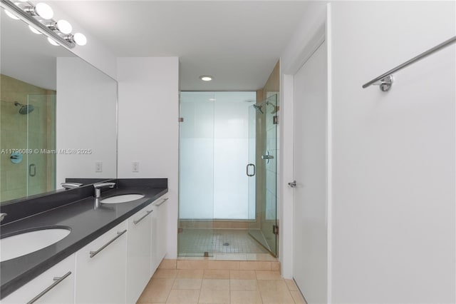 bathroom featuring double vanity, a sink, tile patterned floors, and a shower stall