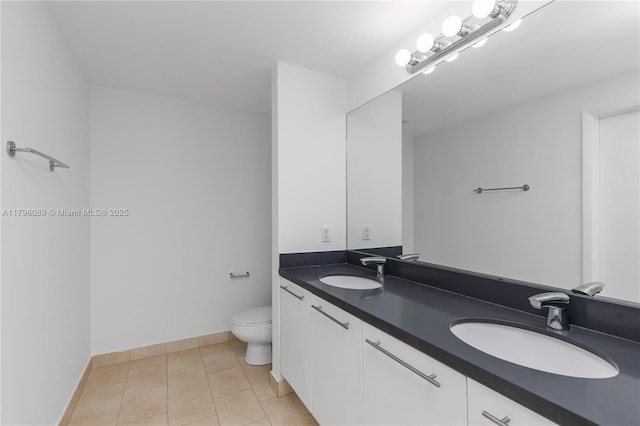 bathroom with a sink, tile patterned floors, toilet, and double vanity