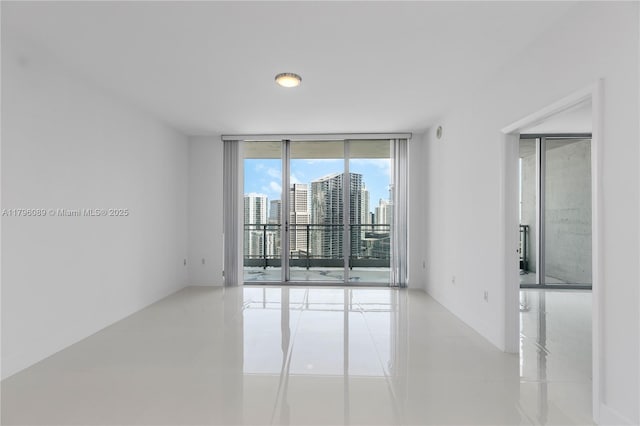 spare room with a view of city, tile patterned floors, and a wall of windows