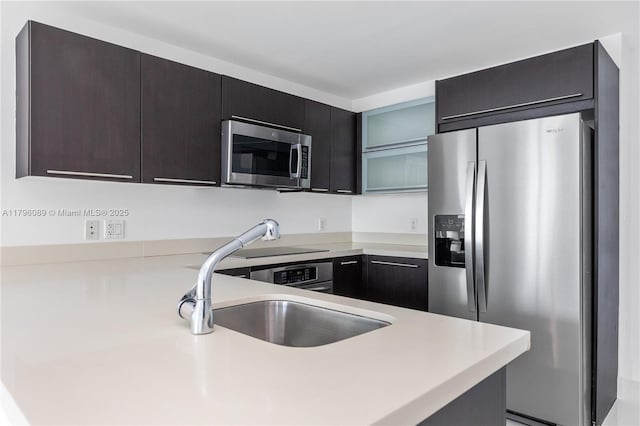kitchen featuring light countertops, a sink, appliances with stainless steel finishes, and a peninsula