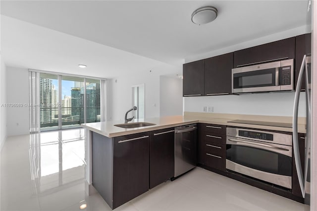 kitchen featuring dark brown cabinetry, a sink, light countertops, a peninsula, and stainless steel appliances