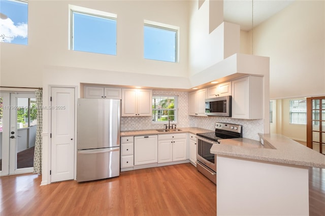 504 Bedford Ave, Weston, FL 33326 - kitchen featuring appliances with stainless steel finishes, a high ceiling, light wood-style floors, and a peninsula