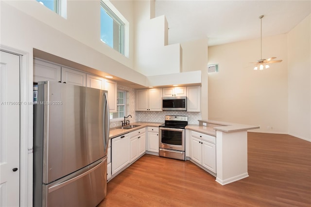 504 Bedford Ave, Weston, FL 33326 - kitchen with stainless steel appliances, a sink, a peninsula, a towering ceiling, and light countertops
