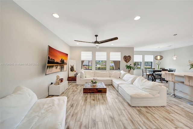 living area with recessed lighting, a ceiling fan, baseboards, and light wood-type flooring