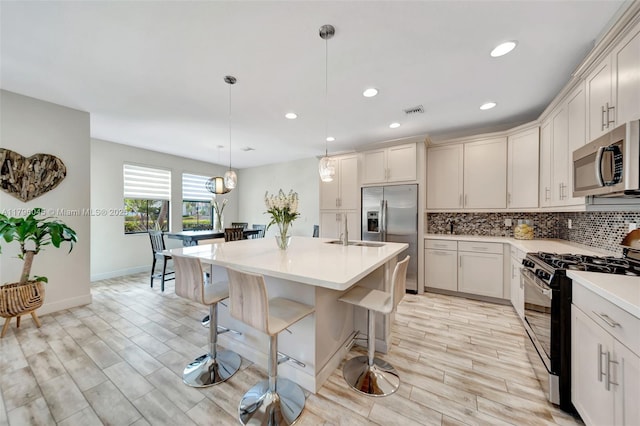 kitchen featuring decorative backsplash, a breakfast bar area, visible vents, light countertops, and stainless steel appliances