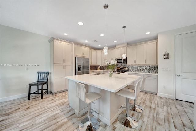kitchen featuring decorative backsplash, appliances with stainless steel finishes, light wood-type flooring, a sink, and recessed lighting
