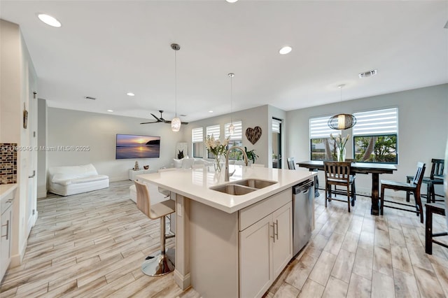 kitchen featuring a sink, open floor plan, light wood-type flooring, stainless steel dishwasher, and visible vents