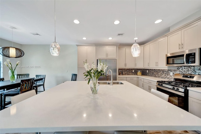 kitchen featuring light countertops, appliances with stainless steel finishes, a spacious island, and visible vents