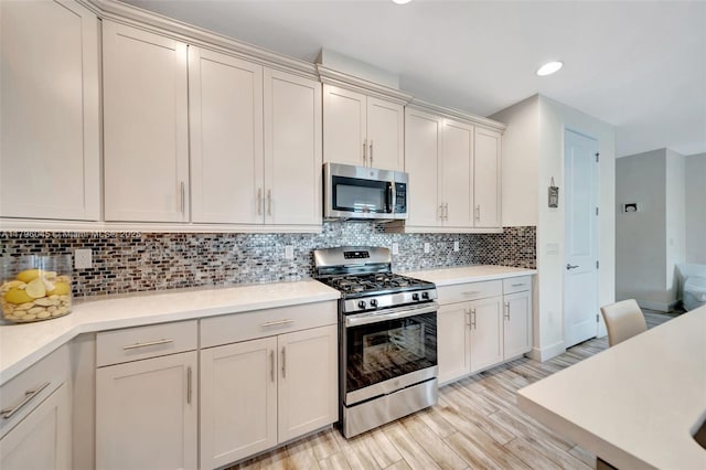 kitchen with light countertops, appliances with stainless steel finishes, light wood finished floors, and tasteful backsplash