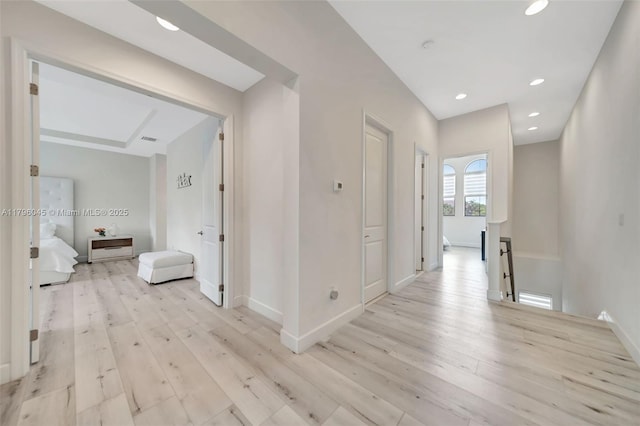 corridor with light wood-style floors, baseboards, recessed lighting, and an upstairs landing