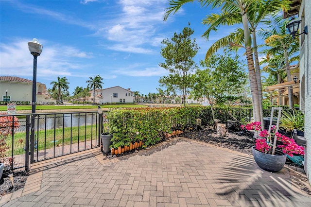 view of patio with a water view and fence