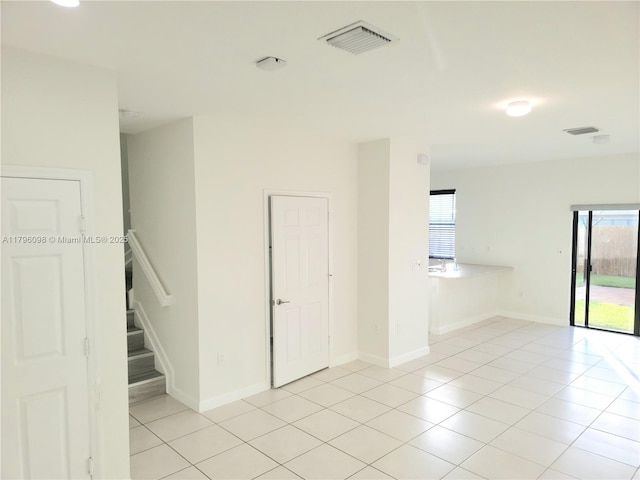 unfurnished room featuring light tile patterned floors, stairway, and visible vents