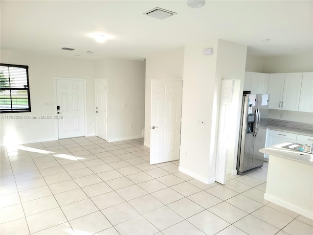kitchen featuring stainless steel fridge, light countertops, light tile patterned flooring, and visible vents