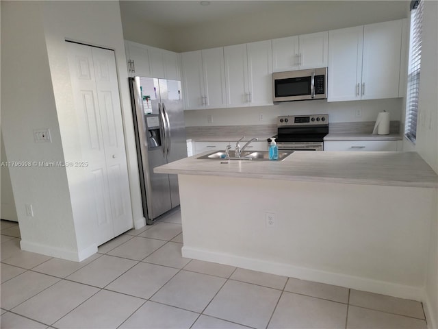 kitchen featuring white cabinets, appliances with stainless steel finishes, a sink, light countertops, and light tile patterned floors