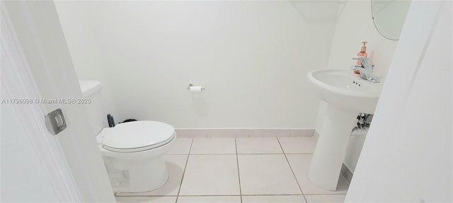 half bath with tile patterned floors, baseboards, and toilet
