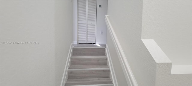 stairway with baseboards, a textured wall, and wood finished floors