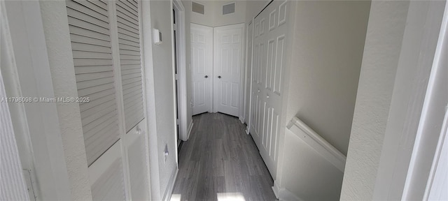 hall with dark wood-style flooring and visible vents