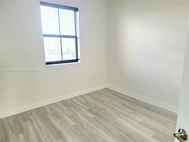 spare room with baseboards and light wood-type flooring