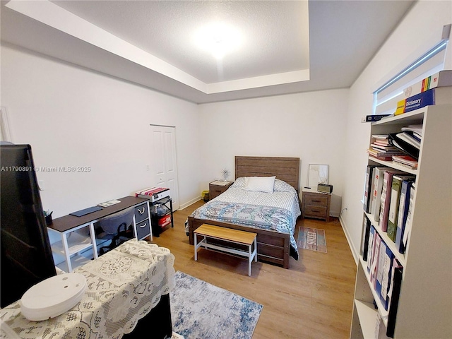 bedroom with wood finished floors and a tray ceiling