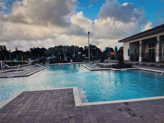 community pool featuring a hot tub and a patio area