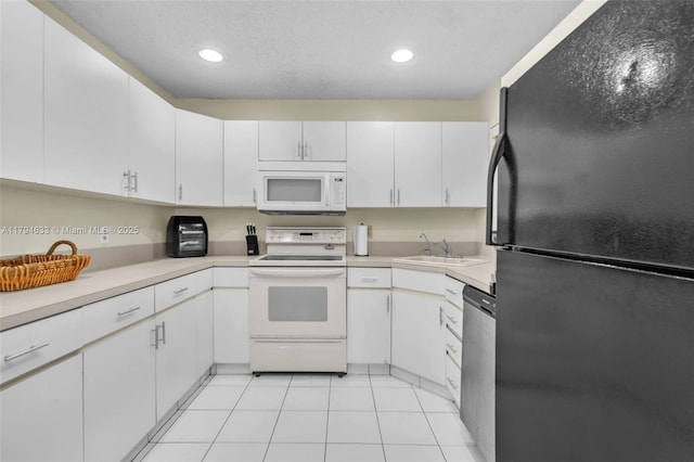 kitchen with light countertops, white cabinets, white appliances, and a sink
