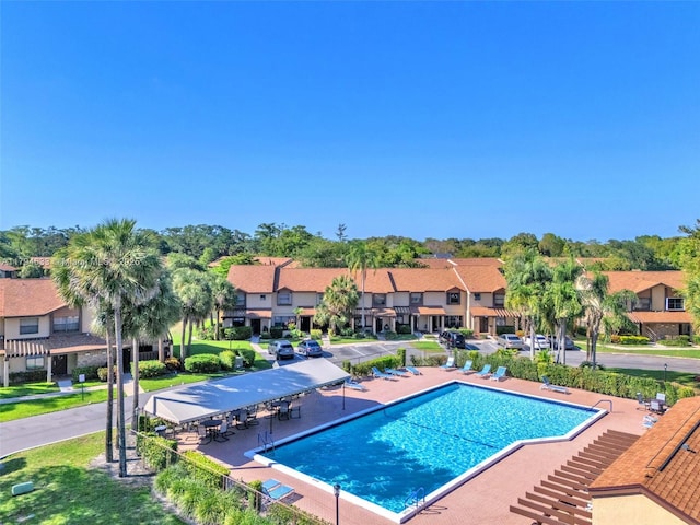 community pool with a residential view and a patio area