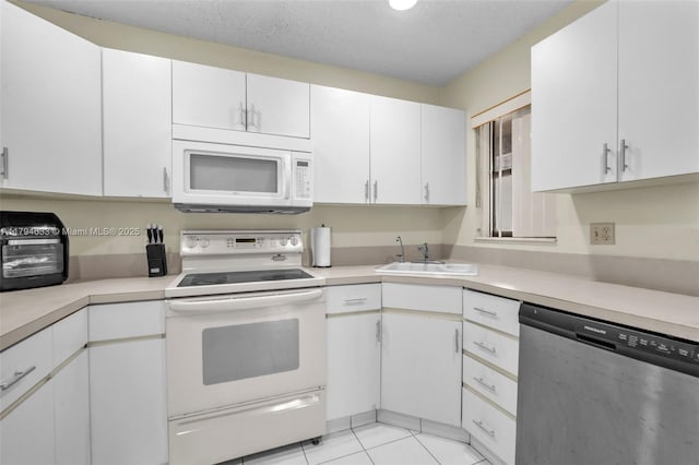 kitchen with white appliances, white cabinetry, a sink, and light countertops