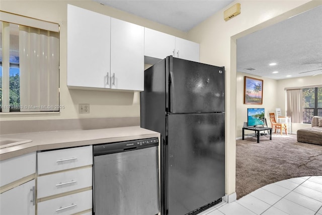kitchen with light colored carpet, stainless steel dishwasher, light tile patterned floors, freestanding refrigerator, and white cabinetry