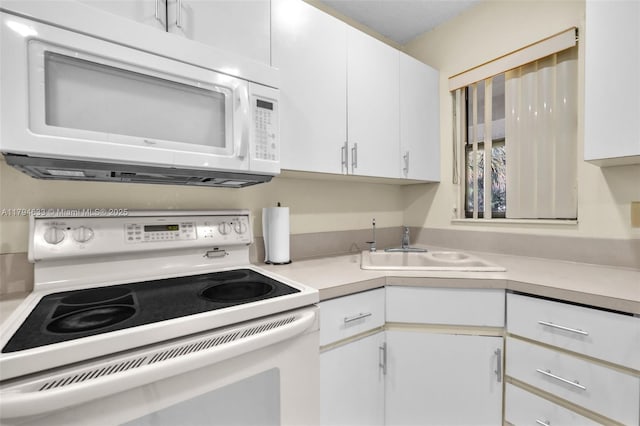 kitchen featuring a sink, white cabinetry, and white appliances