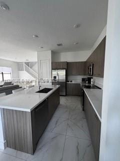 kitchen featuring marble finish floor, modern cabinets, light countertops, stainless steel fridge with ice dispenser, and a large island with sink