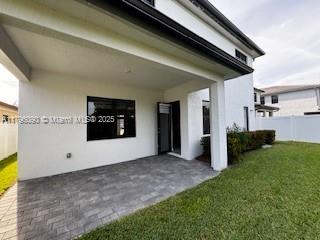 back of house with a lawn, fence, a patio, and stucco siding