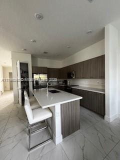 kitchen with a sink, marble finish floor, modern cabinets, and light countertops