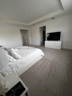 carpeted bedroom with a tray ceiling