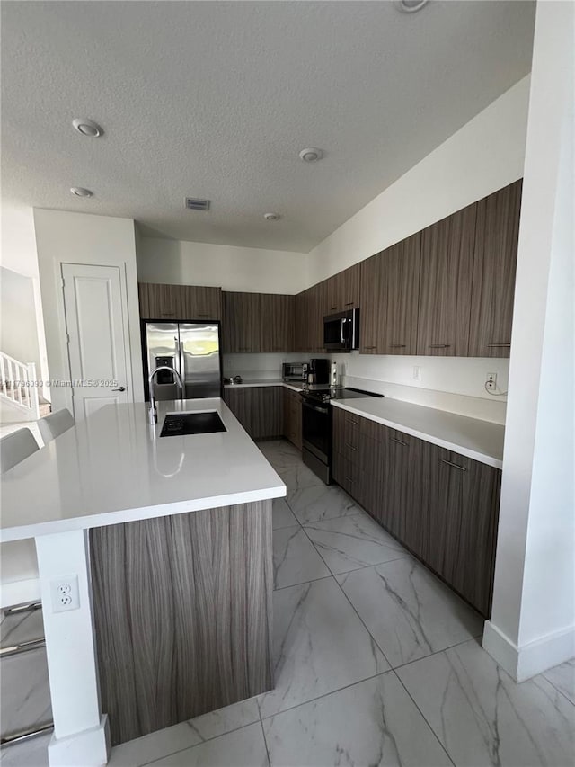 4409 SW 173rd Ave, Miramar, FL 33029 - kitchen with appliances with stainless steel finishes, modern cabinets, light marble finish flooring, a sink, and light countertops