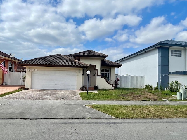 view of front of house with fence, stucco siding, decorative driveway, and a tiled roof