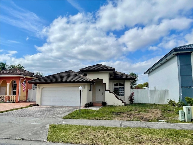 view of front of property with fence, a tile roof, a garage, stucco siding, and decorative driveway