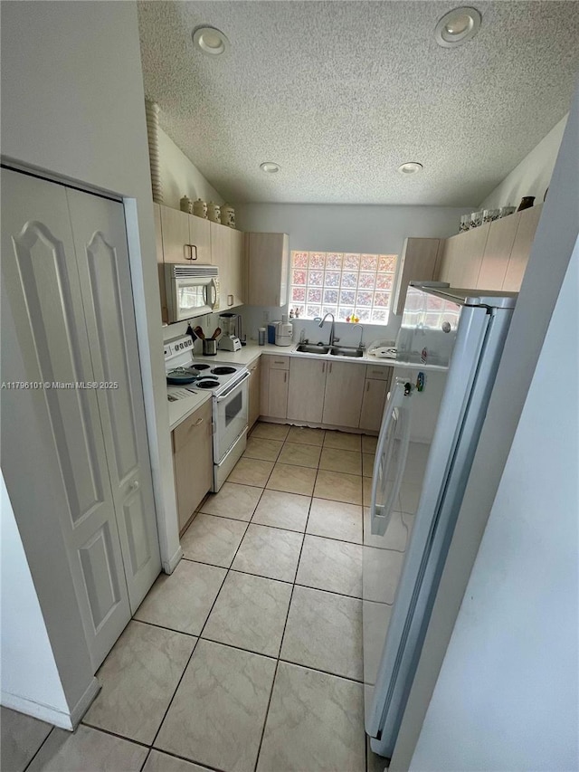 kitchen with a sink, light countertops, white appliances, and a textured ceiling