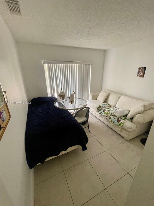 tiled living room with visible vents and a textured ceiling