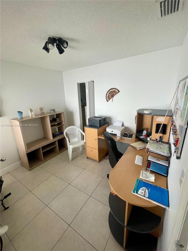 home office featuring a textured ceiling, light tile patterned flooring, and visible vents