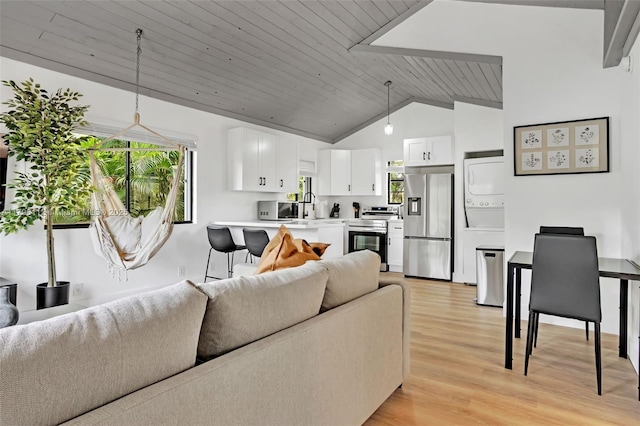 living area with wooden ceiling, stacked washer and clothes dryer, light wood finished floors, and high vaulted ceiling